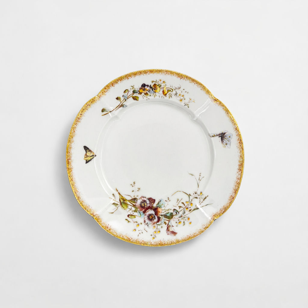 plat rond en porcelaine Limoges William Guerin & Cie à décor de fleurs polychromes et papillon liseré doré D 31,3 cm
